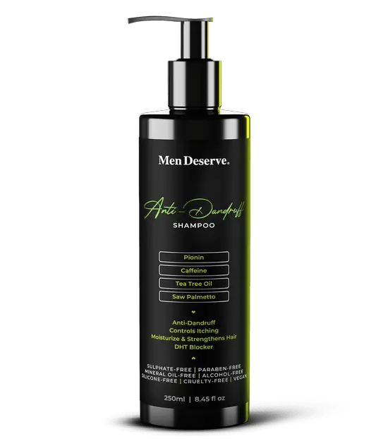 A black bottle of Men Deserve Anti Dandruff Shampoo with a pump dispenser. The label includes green text highlighting the product features such as tea tree oil and a pH balance range.